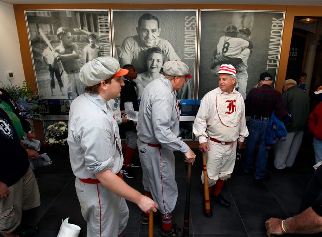 Baseball fans Danny Shaw, left, his father, Brad Shaw, of Manalapan, N.J., and Mark Granieri, of Washington Township, N.J., right, all wear replica 1800s Cincinnati Reds baseball uniforms as they attend a public memorial service at the Yogi Berra Museum for New York Yankees Hall of Fame catcher Yogi Berra, Sunday, Oct. 4, 2015, Little Falls, N.J. The baseball legend known for his quirky sayings died Sept. 22. He was 90.