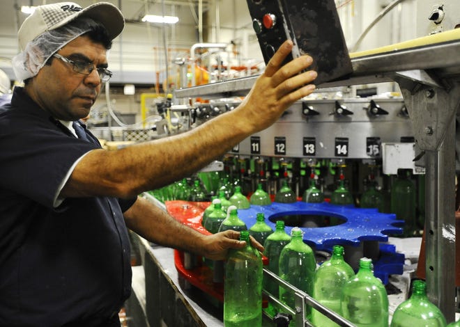 Production supervisor Carlos Flores, who was born in El Salvador, monitors the bottle filler at the Polar Beverages manufacturing plant. T&G Staff/CHRISTINE HOCHKEPPEL