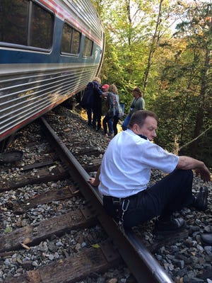 In this photo provided by Brian Bell, a train conductor sits next to an Amtrak train after it derailed on Monday, near Roxbury, Vt., about 20 miles southwest of Montpelier, Vt. The train, the Vermonter, was headed from Vermont to Washington, D.C., when it apparently struck rocks that were on the tracks. No life-threatening injuries were reported. Cathy Bell/Courtesy of Brian Bell via AP