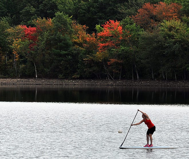 Deborah Lavalle of Northborough paddleboards on Hopkinton Reservoir as fall foliage emerges on Monday.

Daily News Staff Photo / Allan Jung