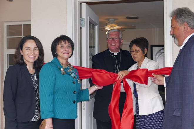 Evelyn Moya, executive director of Cenacle Legal Services, fourth from left, cuts the ribbon in front of a doorway at its new office on the campus of Epiphany Cathedral, 237 N. Nassau Street, Venice. Pictured from left are Tina Mroczkowski, Bonnie Lee Ann Polk, the Most. Rev. Frank Dewane, Moya, and 12th Judicial Circuit Court Judge Frederick P. Mercurio.