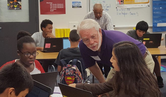 Booker Middle School students Janiah Gregory, left, and Vanessa Mendoza-Martinez work with volunteer Ken Marsh during Tutor Time, part of the Project SUCCESS program. At back table, volunteer George Mims tutors students Anthony Jenkins and Amilcar Gonzalez.