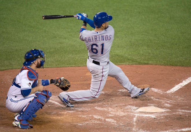 Texas Rangers' Robinson Chirinos, right, hits a two-run home run in front of Toronto Blue Jays catcher Russell Martin during the fifth inning of Game 1 of the American League Division Series in Toronto on Thursday, Oct. 8, 2015