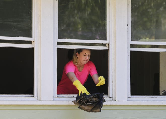 Flood victim Katie Hicks tosses damaged belongs out of a widow as she cleans up, Wednesday, Oct. 7, 2015, in Columbia, S.C. (AP Photo/John Bazemore)