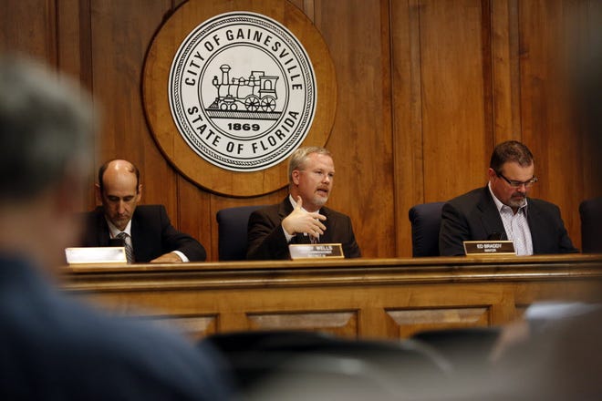 Mayor Ed Braddy, center, flanked by commissioners Randy Wells, left, and Todd Chase, right, addresses attendees during a Gainesville City Commission meeting in 2013.