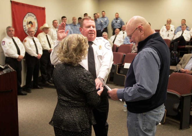 From left, Kim Phelps, holds a bible as her husband Lance Phelps is sworn in by Lubbock City Manager James Loomis. Lance Phelps was named the new Fire Chief during a Changing of the Guard ceremony, Friday, Oct. 9, 2015, in the Fire Training Auditorium in Lubbock, Texas. (Mark Rogers/AJ Media)
