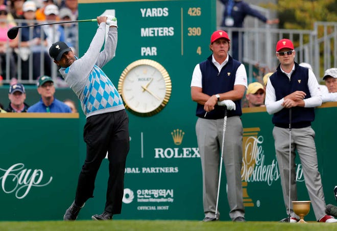 International team player Anirban Lahiri of India hits off the first tee as United States' player's Phil Mickelson and Zach Johnson, right, watch during their four ball match at the Presidents Cup golf tournament at the Jack Nicklaus Golf Club Korea, in Incheon, South Korea, Saturday, Oct. 10, 2015.(AP Photo/Woohae Cho)