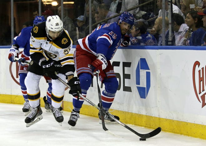 Tommy Cross of the Bruins battles for the puck with Viktor Stalberg of the New York Rangers during a preseason game at Madison Square Garden on Sept. 30.