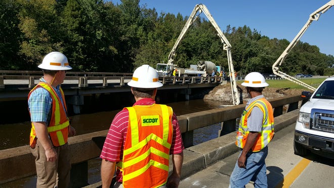 Scott McElveen, Michael Godwin and Wendell Jones of Clarendon Construction monitor concrete pouring underneath bridges along I-95 in Clarendon County. Six concrete pump trucks from United Contractors are working on Sunday, Oct. 11, 2015, to shore up bridge pilings affected by flooding. (Rob Thompson/SCDOT)
