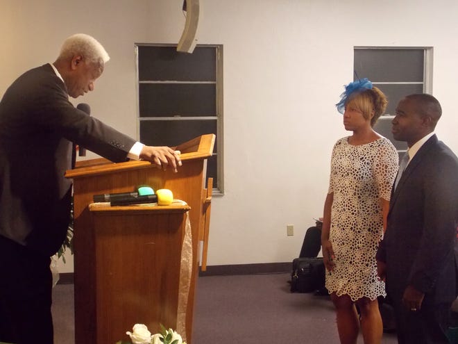 The Rev. Samuel Jones Jr., left, former pastor of Open Door Ministries, gives the charge to his son, Timothy Jones Sr., right, to take over the leadership of the church. At the right of Timothy Jones is his wife, Lady Nona Jones.