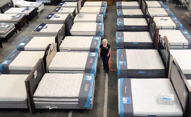 General Manager Michelle Carter walks among mattresses and beds at the new Ashley Furniture Outlet of Kinston on Vernon Avenue.