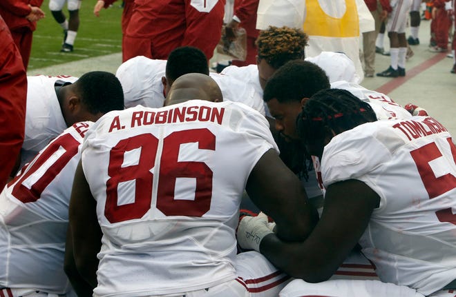 Alabama football players take to their knees for a quiet moment before a game against Georgia in Athens, Ga., on Oct. 3.