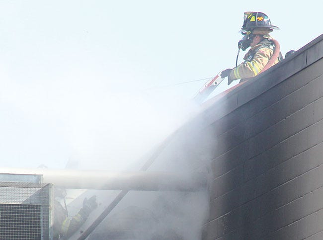 Firefighters work to contain a fire that began in a pump house at Fibre Converters in Constantine Monday afternoon.