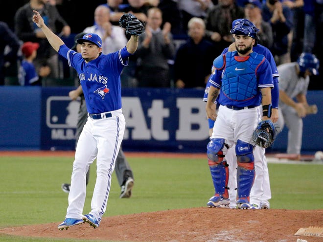Toronto Blue Jays relief pitcher Roberto Osuna, left, celebrates their 7-1 win with catcher Dioner Navarro after Game 5 of baseball's American League Championship Series against the Kansas City Royals on Wednesday, Oct. 21, 2015, in Toronto.