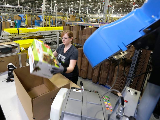 A worker places an item in a box for shipment during a media tour of the new Amazon.com fulfillment center in DuPont, Washington. Amazon, Wal-Mart, Macy's and other retailers are adding warehouse space to handle shipping needs this holiday season. The Associated Press