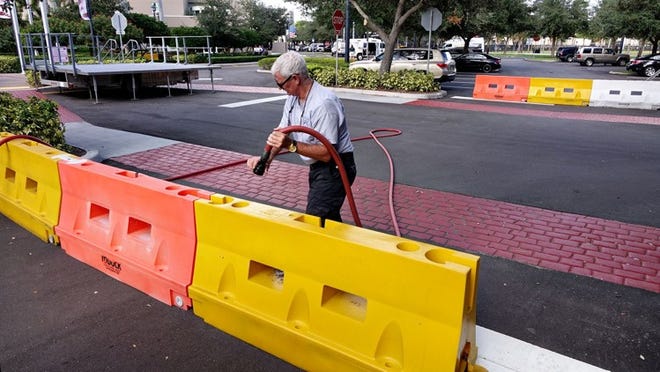 A city employee adds water to portable barriers near a portable stage outside of Palm Beach Gardens City Hall on Oct. 21, 2015. Corey Jones, a 31-year-old Boynton Beach man, was killed by an on-duty Palm Beach Gardens police officer on the PGA Boulevard exit ramp early Sunday morning. (Richard Graulich / The Palm Beach Post)