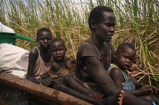 In this photo taken Sunday, Oct. 11, 2015, a displaced woman and her children ride in a wooden canoe through a swamp, where the thick reed marshes protect against attacks, as they flee from Kok Island in Leer county to Nyal in Panyijar county, a trip that costs $20 and many cannot afford, in Unity State, South Sudan. Kok Island in Unity State has become a place of misery, with hundreds of war-weary people reaching there to seek shelter from the violence, just some of the more than 2 million displaced by South Sudan?s civil war, which continues despite a peace accord signed in August.