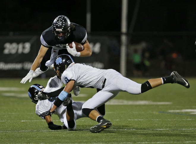 Westerville Central's Andrew Wallace goes airborne for yardage against Hillard Darby's Noah Li, left, and Mason Schmeling.