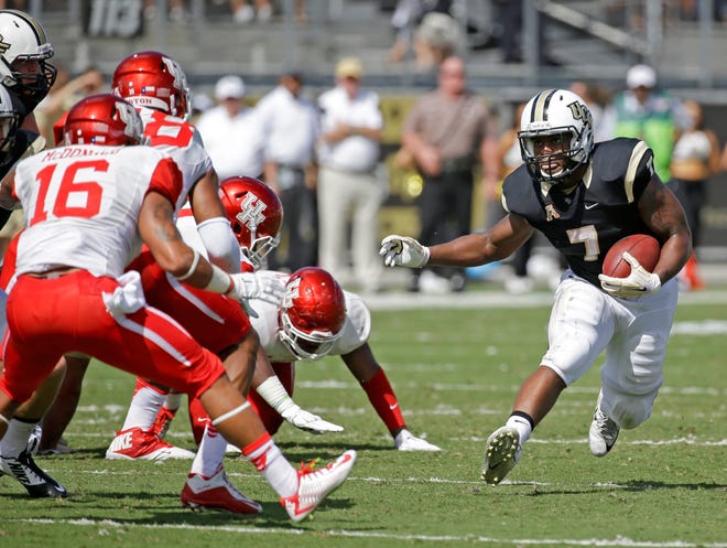 Central Florida running back Dontravious Wilson (7) looks for an opening past Houston safety Adrian McDonald (16) and other defenders during the first half of an NCAA college football game, Saturday, Oct. 24, 2015, in Orlando, Fla.
