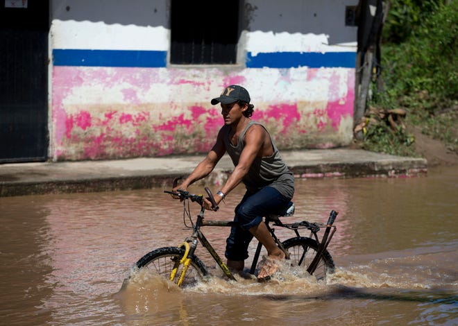 A man bikes down a street through receding floodwaters, two days after the passage of Hurricane Patricia, in the village of Rebalse, outside Cihuatlan, Jalisco State, Mexico, Sunday, Oct. 25, 2015. Patricia roared ashore in Mexico on Friday as a Category 5 terror that barreled toward land with winds up to 200 mph (320 kph). But the arrival of the most powerful hurricane on record in the Western Hemisphere caused remarkably little destruction. (AP Photo/Rebecca Blackwell)