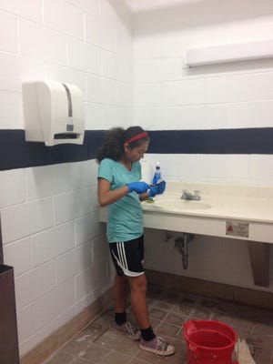 Rocky Bayou Christian School swim team member Lizzy Cannon works on the sink in one of the locker rooms at the old YMCA. The swim team worked to clean up the facility on Saturday.