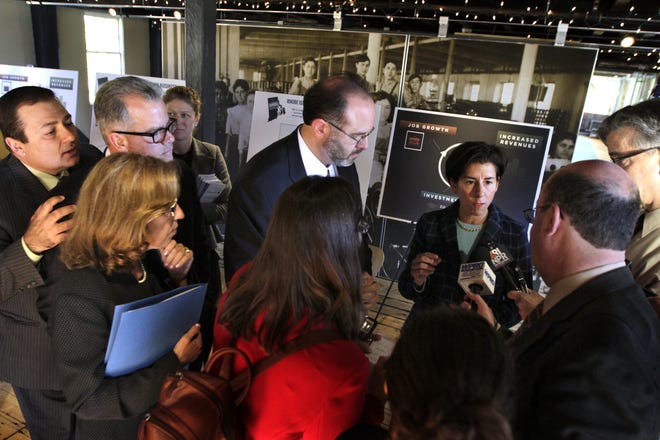 Governor Raimondo speaks with reporters at the Slater Mill in Pawtucket during Monday's tax-credit incentives program. Listening in are other state officials. The Providence Journal / Kris Craig