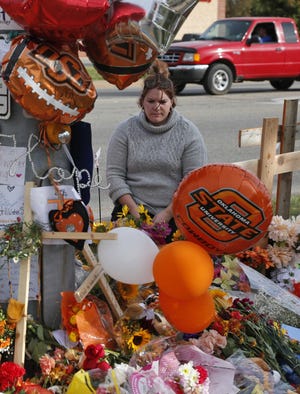 Stefanie Alexander, who witnessed the parade crash on Saturday in Stillwater, Okla., kneels at a makeshift memorial to the victims.