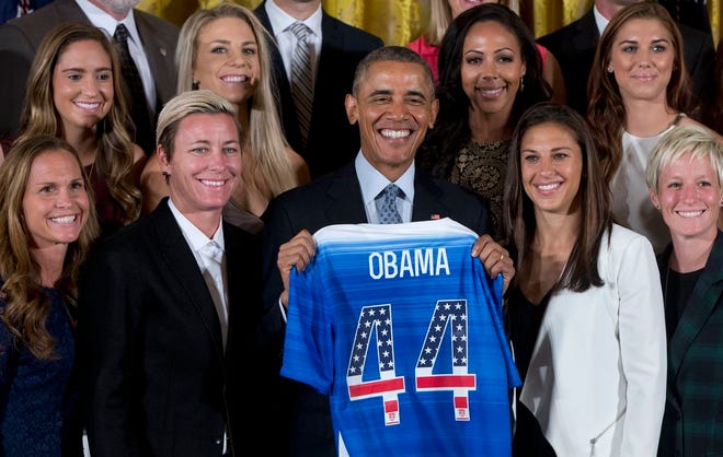 President Barack Obama poses for photos with a jersey he received from head coach Jill Ellis as he welcomed the U.S. Women's National Soccer Team, Tuesday, Oct. 27, 2015, in the East Room of the White House in Washington during a ceremony to honor the team and their victory in the 2015 FIFA Women's World Cup. Standing with Obama, from left are, Christie Rampone, Morgan Brian, Abby Wambach, Julie Johnston, Obama, Sydney Leroux, and Carli Lloyd, Alex Morgan, and Megan Rapinoe. (AP Photo/Carolyn Kaster)