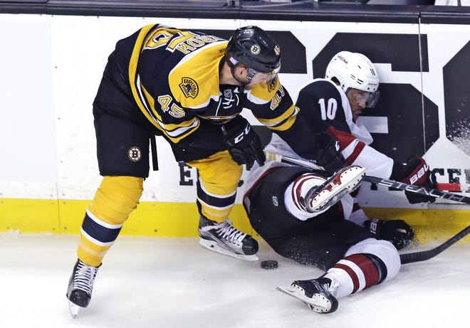 Coyotes left wing Anthony Duclair (10) hits the ice as Bruins defenseman Joe Morrow (45) tries to dig out the puck during the first period. The Associated Press