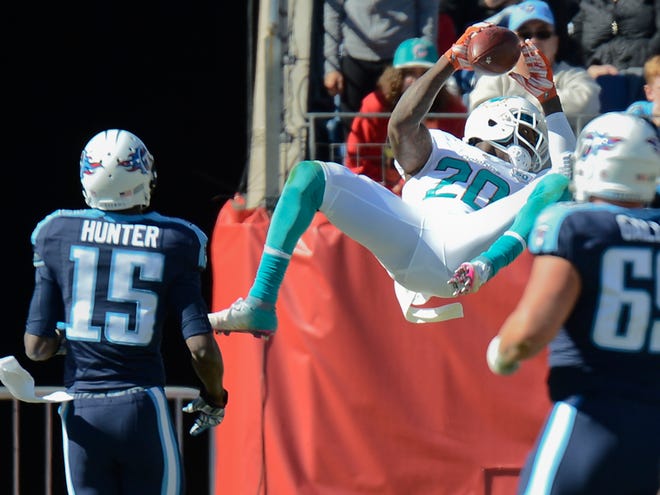 Miami Dolphins strong safety Reshad Jones (20) leaps into the end zone after returning a pass interception 30 yards for a touchdown against the Tennessee Titans in the second half of an NFL football game Sunday, Oct. 18, 2015, in Nashville, Tenn. Defending for the Titans are Justin Hunter (15) and Andy Gallik.