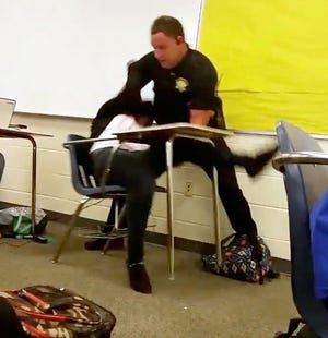 In this Monday, Oct, 26, 2015 photo made from video taken by a Spring Valley High School student, Senior Deputy Ben Fields tries to forcibly remove a student who refused to leave her high school math class, in Columbia S.C.