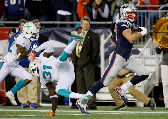 New England Patriots tight end Rob Gronkowski runs past Miami Dolphins free safety Michael Thomas as he heads to the end zone for a touchdown in the first half an NFL football game, Thursday, Oct. 29, 2015, in Foxboro.