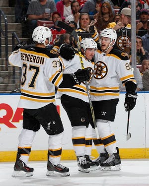 Boston Bruins forward Brad Marchand (63) is congratulated by Kevan Miller (86) and center Patrice Bergeron (37) after he scored his second goal against the Florida Panthers during the second period of an NHL hockey game, Friday, Oct. 30, 2015, in Sunrise, Fla. (AP Photo/Joel Auerbach)