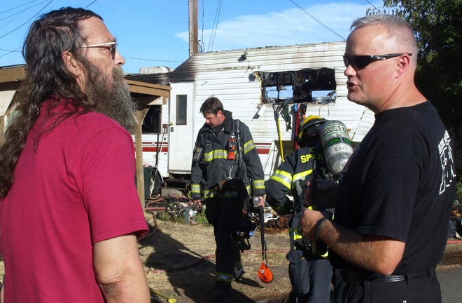 Ray Rossi talks with an investigator from the Eugene Springfield Fire Department on July 30 after his house burned down while he was away. (Randi Bjornstad/The Register-Guard)