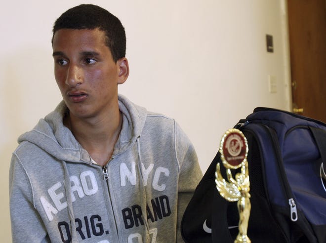 An April 18, 2013, photo of Salah Eddin Barhoum sitting in his apartment in Revere, Mass., with one of the trophies he won in an athletic competition and the bag he was carrying near the finish line of the Boston Marathon. File Photo/The Associated Press