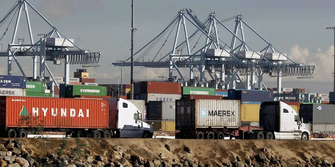 Trucks hauling containers leave the Port of Los Angeles. File Photo/The Associated Press
