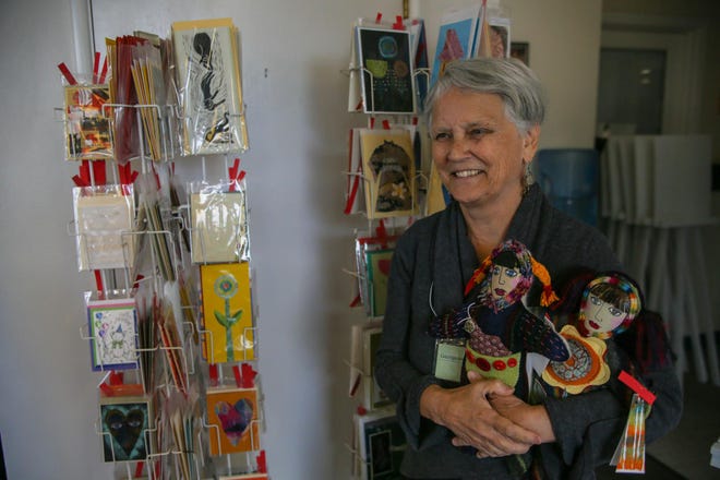 ArtChic Georgeanne Cooper holds up her handmade dolls next to her display of greeting cards at the 11th annual ArtChics Art Sale and Benefit on Saturday at the Lincoln Art Gallery in downtown Eugene. A portion of the proceeds from this benefit will go towards the Oregon Supported Living Program Arts and Culture Program. (Mary Jane Schulte/The Register-Guard)