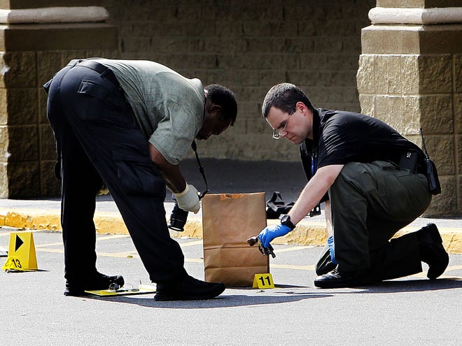 In this May 12 file photo, officials examine a gun at the scene of a shooting outside the Winn-Dixie on North Main Street in Gainesville.