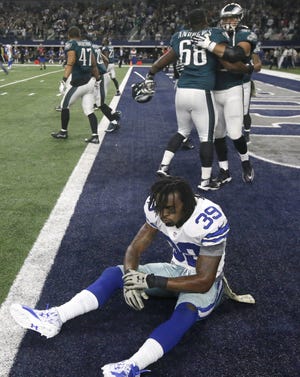 Dallas Cowboys' Brandon Carr (39) sits on the field as Philadelphia Eagles' Josh Andrews (68) celebrates with teammates after the Eagles' 33-27 win in overtime Sunday.