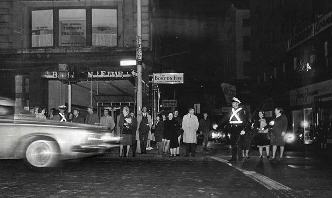 A police officer wearing a reflective belt directs pedestrians and traffic on Tremont Street in Boston during a power failure Nov. 9, 1965.