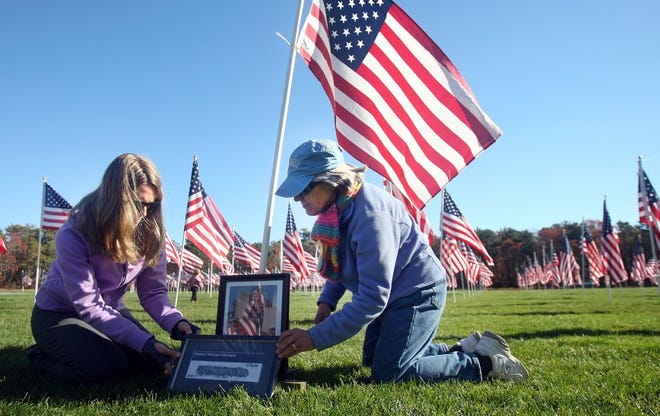 Christine Sweet, left, of South Dennis, helps her mother, Joan Carleton, set up a display at Johnny Kelley Park in Dennis at the flag honoring Joan's brother, Frederick N. Curtis, killed in action in Vietnam on May 28th, 1969. The third annual Field of Honor and Healing at the park commemorates the sacrifices of our military, veterans and first responders.