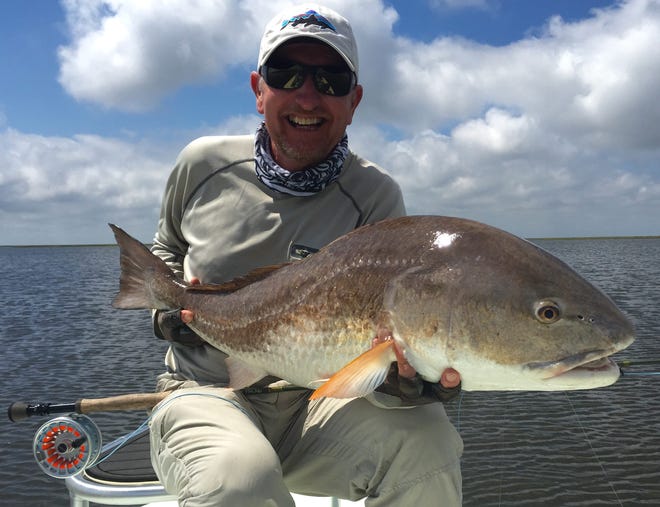 Guide Rocky Thickstun poses with a 28-pound redfish that was hooked on a four-inch articulated fly in Biloxi Marsh on the Gulf of Mexico, southeast of New Orleans. The Louisiana marsh boasts the largest redfish in the world. PETER OTTESEN/FOR THE RECORD