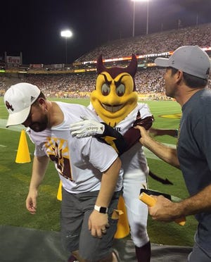 This photo courtesy of David Schapira shows ASU's mascot Sparky jumping on David Schapira at a Arizona State University football game on Sept. 18, 2015 in Tempe, Ariz. Schapira, a Tempe City Councilman, has filed a claim against Arizona State University for injuries suffered when the school mascot leapt on him on Wednesday, Nov. 11, 2015 The costumed character leapt on him at a football game two months after he underwent back surgery. The prank leap set back his recovery and led to a four-day hospital stay and physical therapy, Schapira said. (Courtesy of David Schapira via AP)