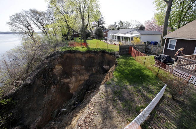 Lynne O'Dell walks past a sinkhole behind her Florence home on Front Street in April 2015. O'Dell and her husband, Christopher, and neighbor Gene Woodlee were told to evacuate their homes because of the danger.