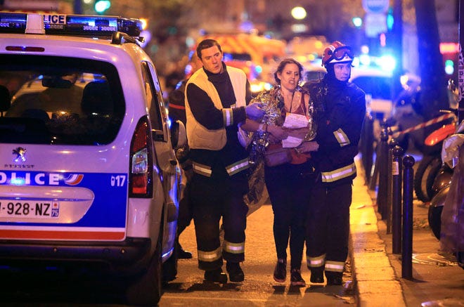 Rescue workers help a woman outside the Bataclan theater in Paris after Friday's shooting.