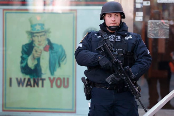 A heavily armed New York city police officer with the Strategic Response Group stands guard at the armed forces recruiting center in New York's Times Square, Saturday, Nov. 14, 2015. Police in New York say they've deployed extra units to crowded areas of the city "out of an abundance of caution" in the wake of the attacks in Paris, France. A New York Police Department statement released Friday stressed police have "no indication that the attack has any nexus to New York City." (AP Photo/Mary Altaffer)