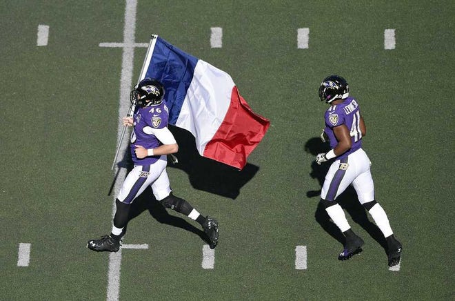 Baltimore Ravens long snapper Morgan Cox, left, runs onto the field with the flag of France in front of teammate Anthony Levine before an NFL football game against the Jacksonville Jaguars, Sunday, Nov. 15, 2015, in Baltimore. (AP Photo/Nick Wass)