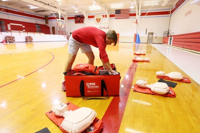 Trinity physical education teacher Jan Frieb opens up the CPR in Schools Training Kit that was recently gifted to the school. The kit was developed by the American Heart Association.