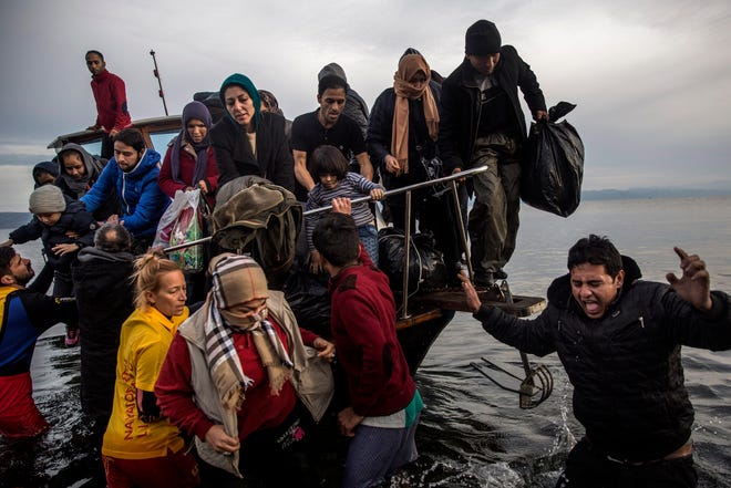 Migrants disembark from a small boat after their arrival from the Turkish coast on the northeastern Greek island of Lesbos Monday, Nov. 16, 2015. Greek authorities say 1,244 refugees and economic migrants have been rescued from frail craft in danger over the past three days in the Aegean Sea, as thousands continue to arrive on the Greek islands. (AP Photo/Santi Palacios)