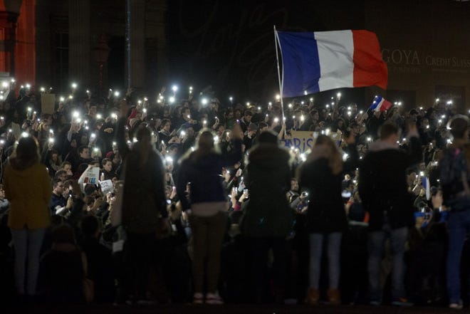 People, many of whom are French, hold up their lit phones as they take part in a vigil in solidarity with France in London on Saturday, Nov. 14, 2015, the day after the deadly attacks in Paris.